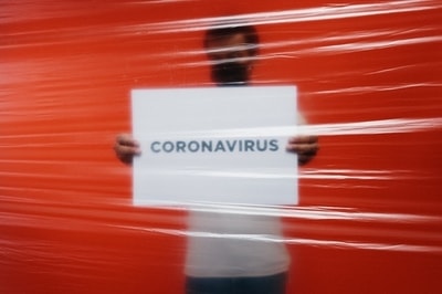 Mężczyzna w masce z napisem coronavirus odgrodzony folią