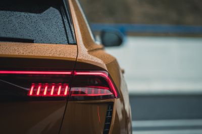 Tył złotego nowoczesnego samochodu z włączonymi czerwonymi światłami LED