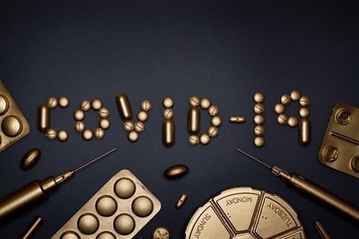 Leki, strzykawki i napis COVID-19 ze złota