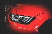Czerwony sportowy samochód widok przedniej maski, lampy i atrapy