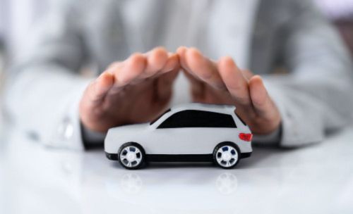 Dłonie kobiety w białej koszuli osłaniające biały samochód zabawkę