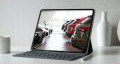 Tablet stojący na białym biurku wyświetlający samochody poleasingowe stojące w salonie