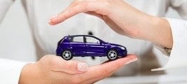 Kobiece dłonie chroniące zabawkowy samochód osobowy symbolizujące ochronę ubezpieczenia GAP