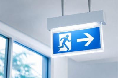 Podświetlony znak wyjścia ewakuacyjnego symbolizujący bezpieczne i przedterminowe zakończenie umowy leasingu.