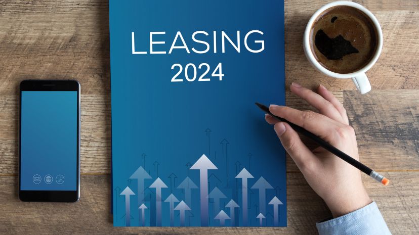 Biurko z dokumentem o tytule "LEASING 2024", telefonem komórkowym i filiżanką kawy