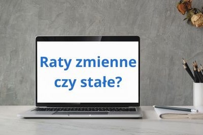 Otwrty i włączony laptop stojący na biurku z napisem Raty zmienne czy stałe?