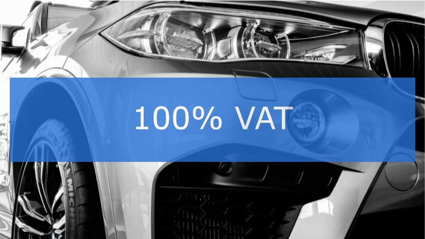 Samochód osobowy z nałożonym napisem '100% VAT' na niebieskim tle