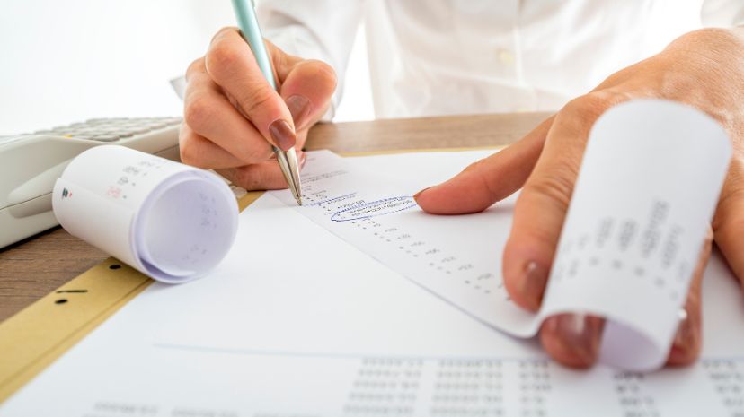 Przedsiębiorca oblicza koszty i przychody firmy, w tle rachunki i kalkulator.