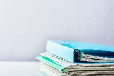 Stos dokumentów i segregator na biurku – procedury i umowy leasingowe