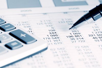 Kalkulator, długopis i tabela z danymi liczbowymi, symbolizujące analizę finansową lub przygotowywanie raportów księgowych