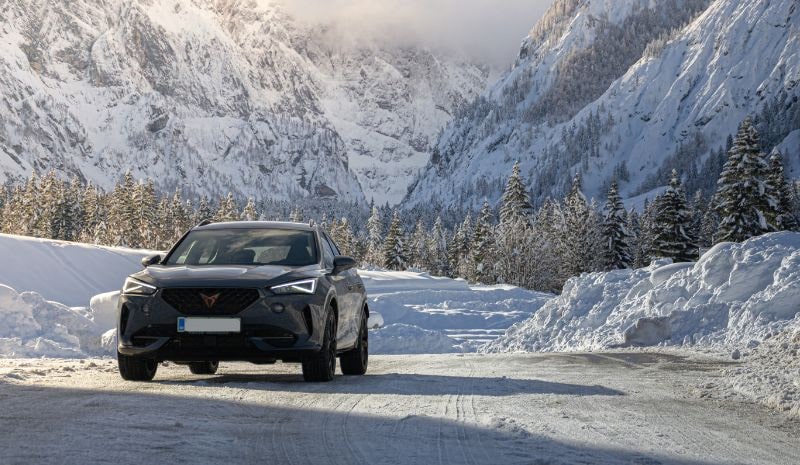 Cupra Formentor jadąca zimą drogą poprzez wysokie, ośnieżone góry