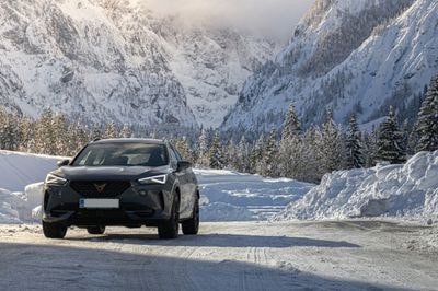 Cupra Formentor jadąca zimą drogą poprzez wysokie, ośnieżone góry